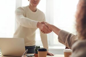 pexels-photo-3184465-3184465 Close-up of professionals shaking hands over coffee in a modern office.